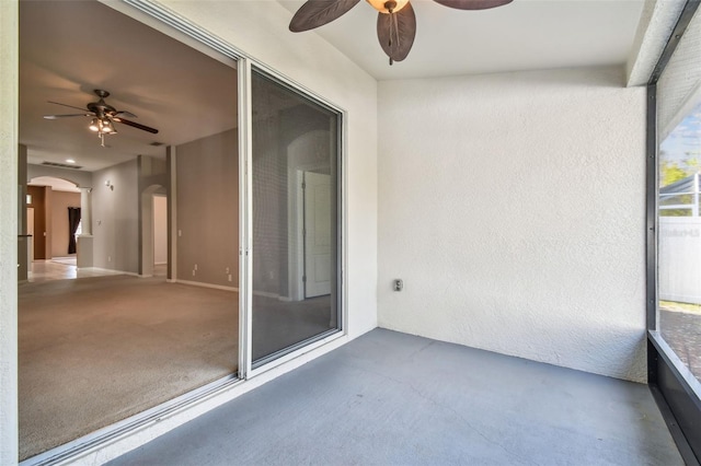 unfurnished sunroom with arched walkways and ceiling fan