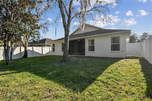 back of property featuring a fenced backyard, a lawn, and stucco siding