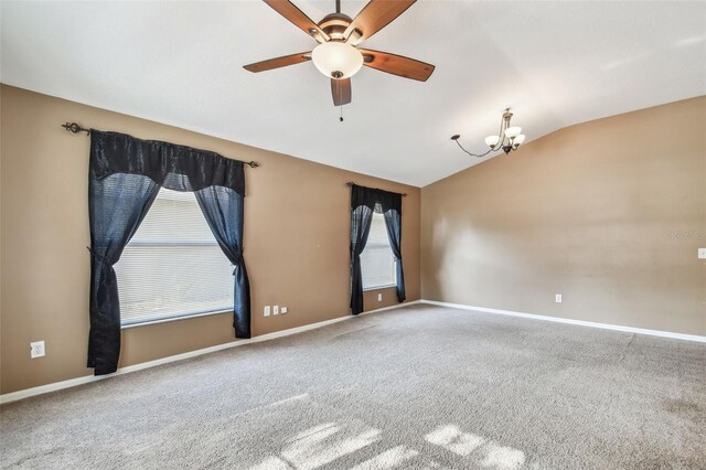 carpeted spare room with vaulted ceiling, ceiling fan with notable chandelier, and baseboards