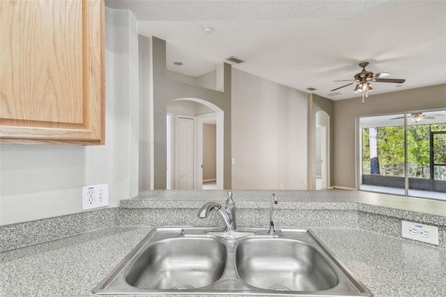 kitchen featuring arched walkways, light countertops, a sink, and visible vents