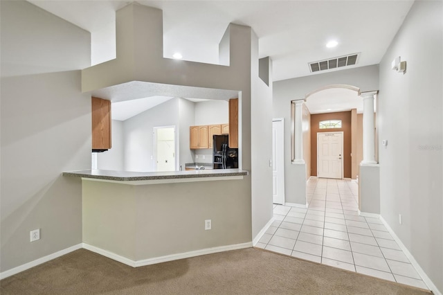 kitchen featuring arched walkways, decorative columns, visible vents, light tile patterned flooring, and black fridge