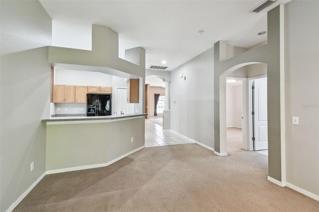 interior space with arched walkways, light colored carpet, visible vents, black fridge with ice dispenser, and light brown cabinetry