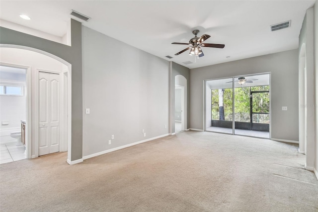 carpeted spare room featuring arched walkways, visible vents, and baseboards