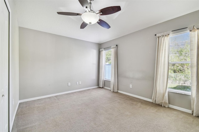 spare room with carpet, a ceiling fan, and baseboards