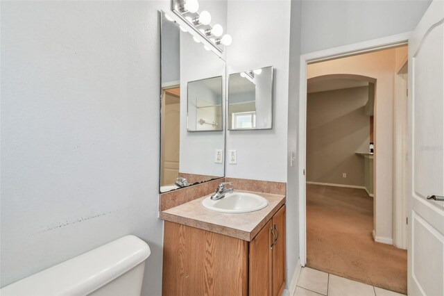 half bath with tile patterned flooring, vanity, and toilet