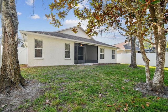 rear view of house with fence private yard, a lawn, and stucco siding