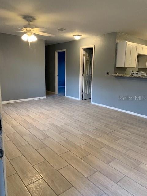 unfurnished living room featuring a ceiling fan, light wood-style flooring, and baseboards