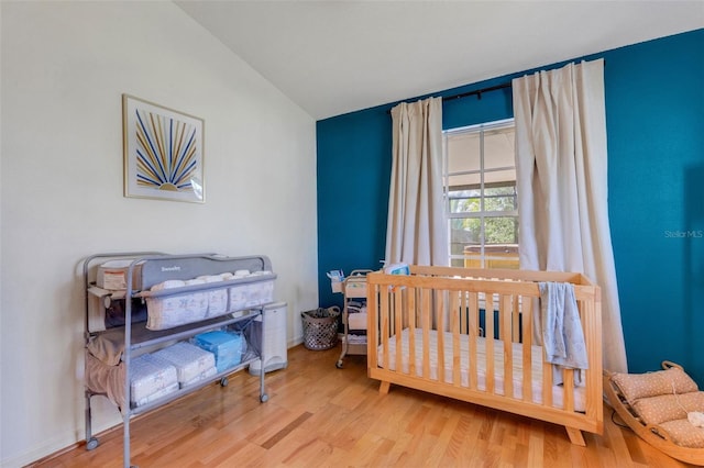 bedroom featuring lofted ceiling, baseboards, and wood finished floors