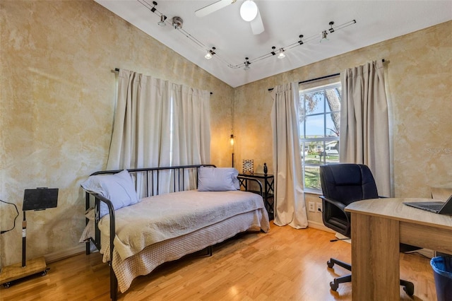 bedroom with lofted ceiling, ceiling fan, track lighting, and wood finished floors