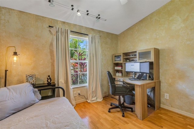 bedroom with vaulted ceiling, baseboards, and wood finished floors