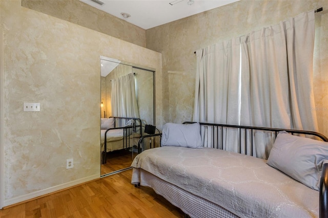 bedroom with a closet, wood finished floors, and baseboards