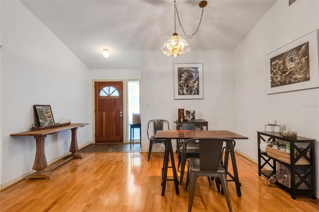 dining area with a chandelier, light wood-style flooring, and baseboards