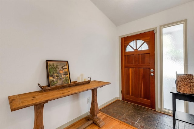 entrance foyer featuring lofted ceiling and baseboards