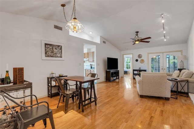 living room featuring ceiling fan with notable chandelier, french doors, light wood-type flooring, and visible vents