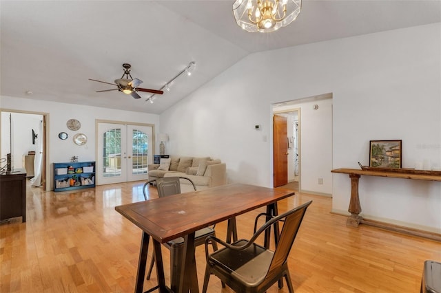 dining space featuring lofted ceiling, french doors, ceiling fan with notable chandelier, and light wood-type flooring