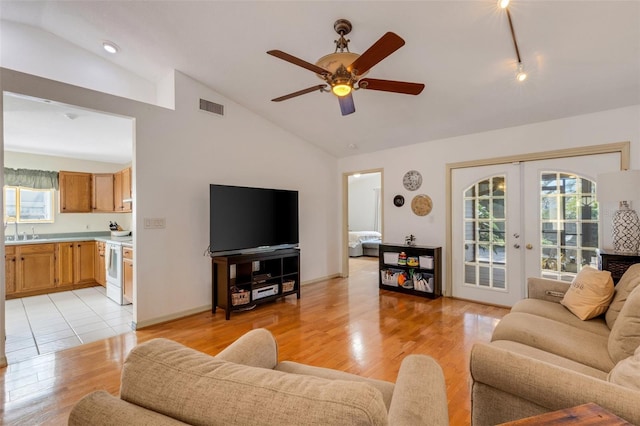 living area featuring french doors, visible vents, vaulted ceiling, ceiling fan, and light wood-type flooring