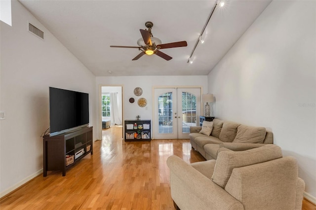 living room featuring light wood-style flooring, visible vents, vaulted ceiling, french doors, and track lighting