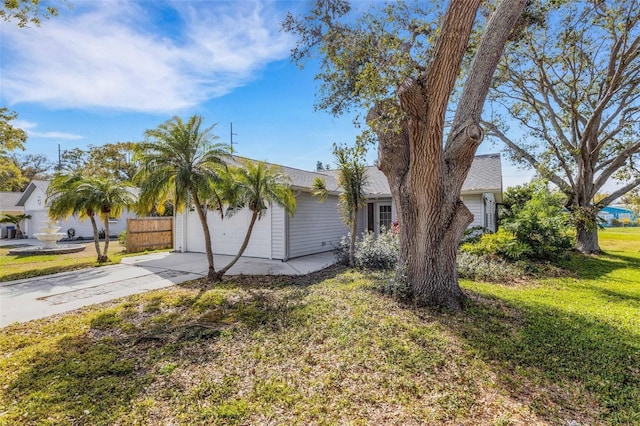 view of side of property with a garage, a lawn, driveway, and fence