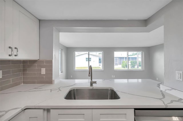 kitchen featuring dishwashing machine, a wealth of natural light, a sink, and white cabinetry