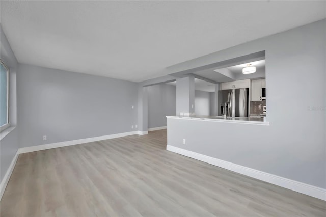 unfurnished living room featuring light wood-style floors and baseboards