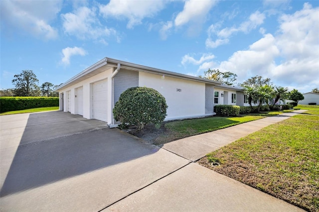 view of side of property featuring a garage, a lawn, and brick siding