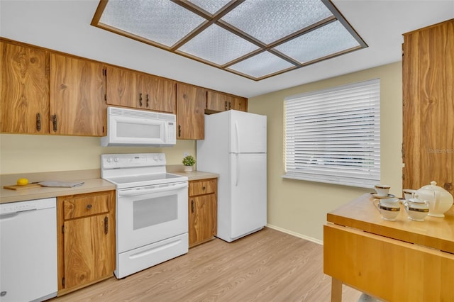 kitchen with light countertops, light wood-style flooring, brown cabinetry, white appliances, and baseboards