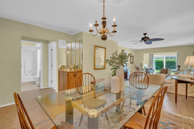 dining area featuring ceiling fan with notable chandelier, wood finished floors, and baseboards