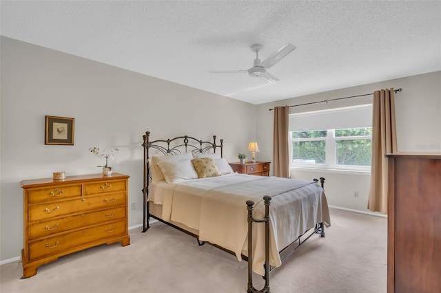 bedroom with a textured ceiling, baseboards, a ceiling fan, and light colored carpet