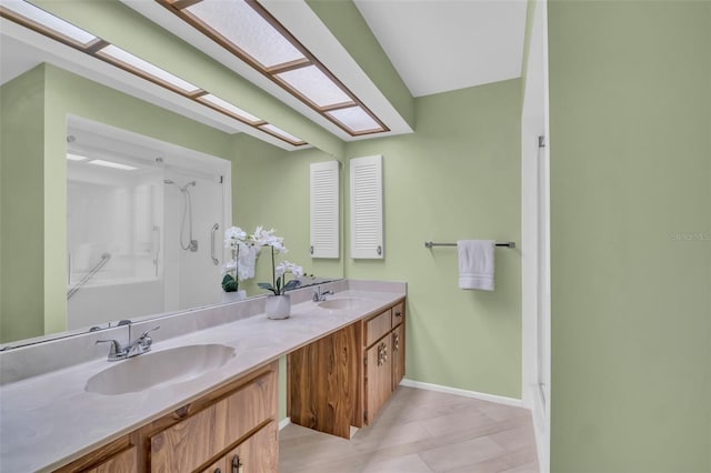 full bath with a shower, double vanity, a skylight, and a sink