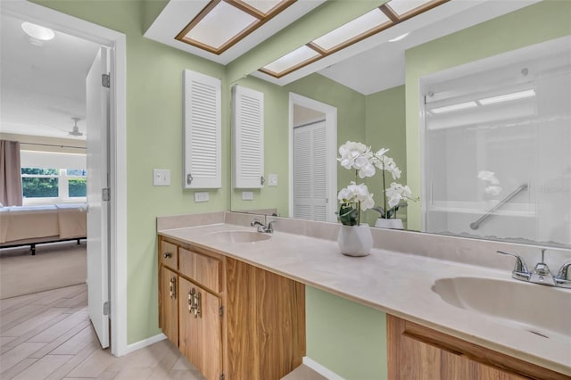 ensuite bathroom featuring double vanity, ensuite bath, a sink, and baseboards