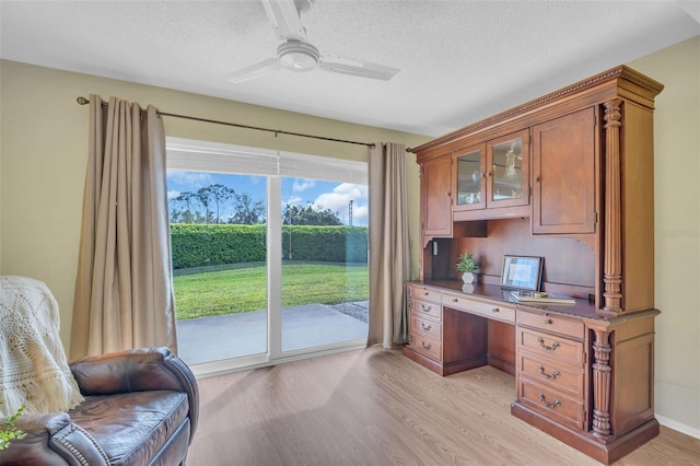 office area with light wood-style floors, ceiling fan, built in desk, and a textured ceiling