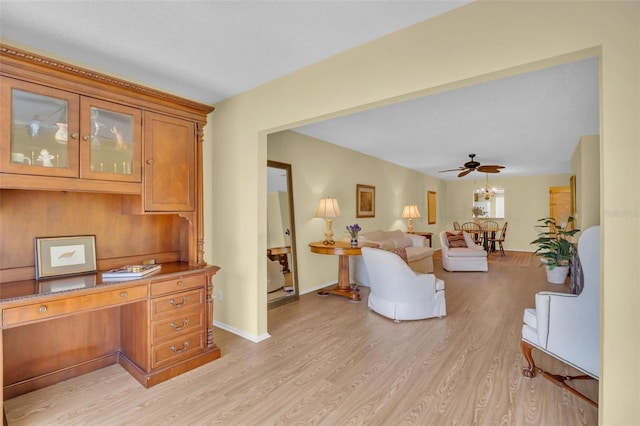 living area featuring light wood-style floors, ceiling fan, and baseboards