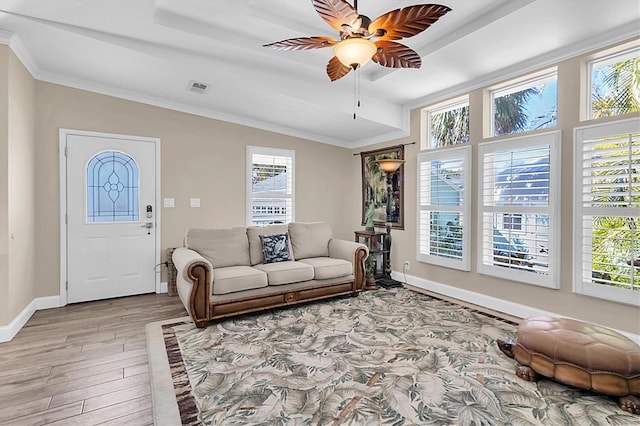 living area with baseboards, visible vents, a ceiling fan, crown molding, and light wood-style floors