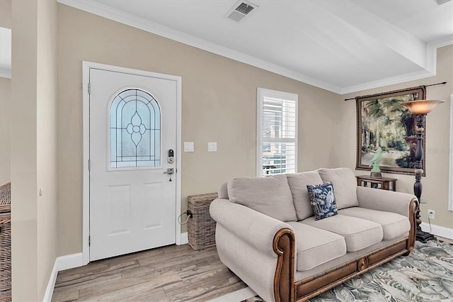 foyer featuring ornamental molding, light wood-type flooring, visible vents, and baseboards