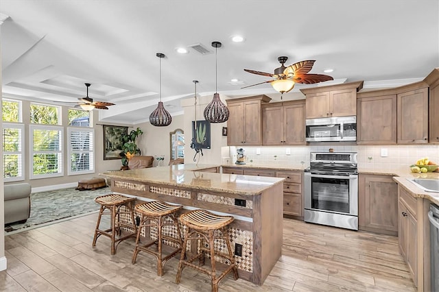 kitchen with appliances with stainless steel finishes, a tray ceiling, visible vents, and backsplash