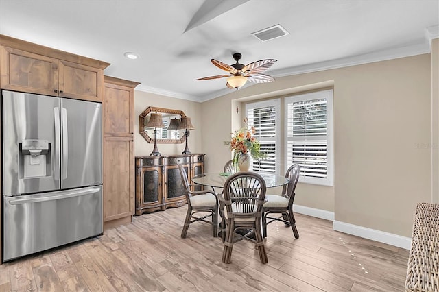 dining area with light wood finished floors, visible vents, ornamental molding, a ceiling fan, and baseboards