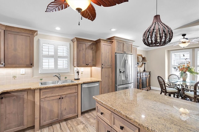 kitchen featuring light wood-style flooring, stainless steel appliances, a sink, backsplash, and crown molding