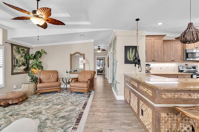 interior space featuring appliances with stainless steel finishes, light stone counters, backsplash, and ornamental molding