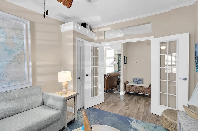 living area with ornamental molding, french doors, ceiling fan, and wood finished floors