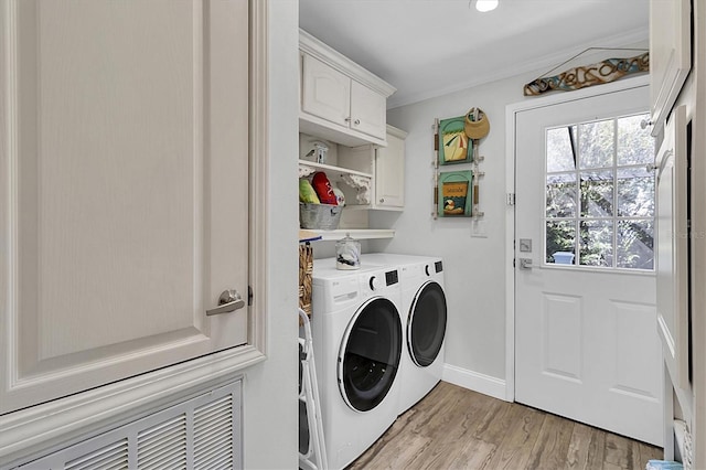 clothes washing area with crown molding, light wood finished floors, cabinet space, washing machine and dryer, and baseboards