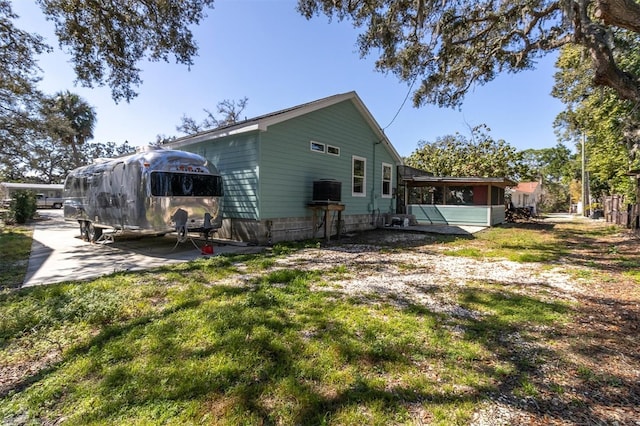 rear view of property featuring a lawn, a patio area, and a sunroom