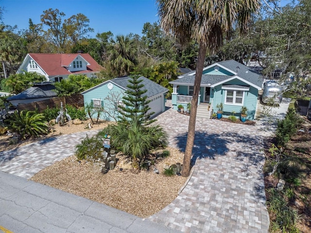 ranch-style home with covered porch, a garage, a shingled roof, an outdoor structure, and decorative driveway