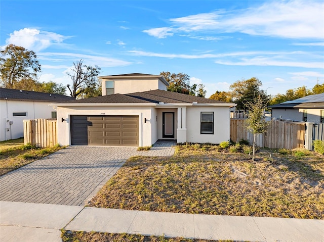 view of front of home featuring decorative driveway, an attached garage, fence, and stucco siding