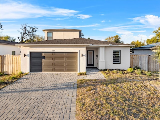 view of front of home featuring a garage, fence, decorative driveway, and stucco siding