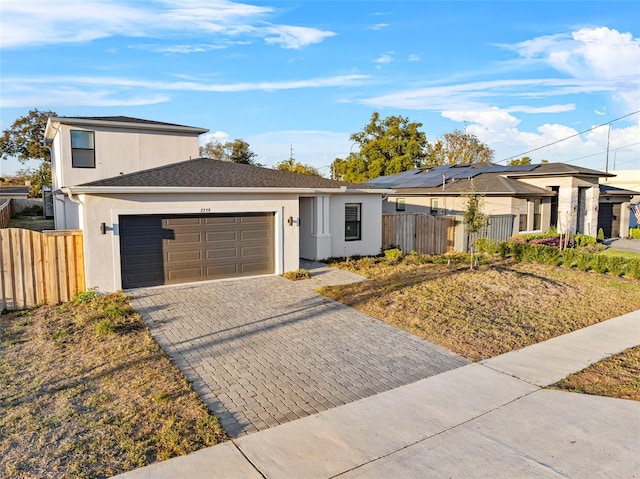 view of front of house featuring a garage, decorative driveway, fence, and stucco siding