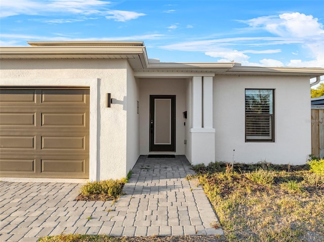 property entrance with an attached garage and stucco siding