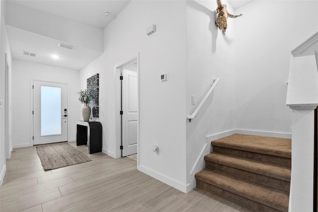 entrance foyer with stairs, light wood-style floors, visible vents, and baseboards