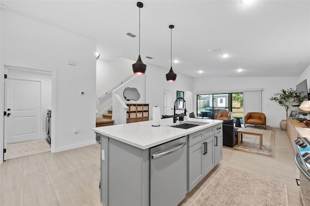 kitchen featuring light countertops, gray cabinetry, appliances with stainless steel finishes, a sink, and an island with sink