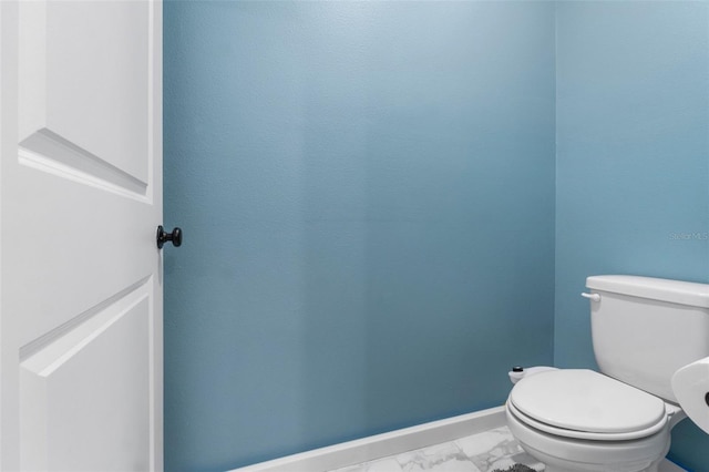 bathroom with toilet, marble finish floor, and baseboards