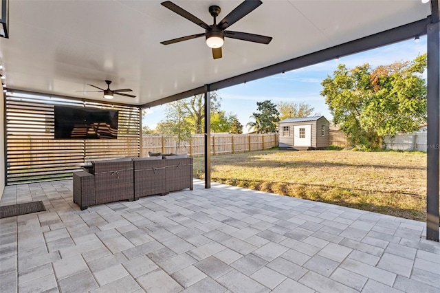 view of patio featuring an outbuilding, a fenced backyard, an outdoor hangout area, a ceiling fan, and a storage unit